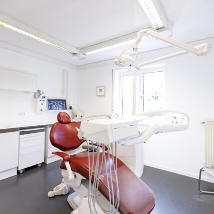 Abbildung Behandlungszimmer mit rotem Zahnarztstuhl