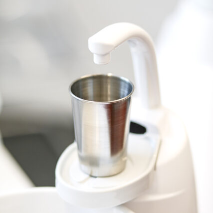 Nahaufnahme Wasserhahn mit Becher am Speibecken